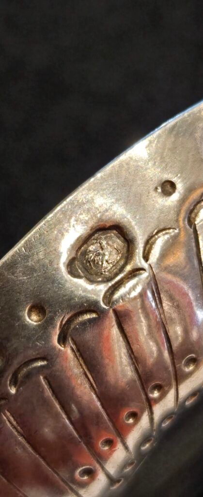 20260313 161748 Exceptionnel petit taste-vin (tâte-vin) de dégustation en argent massif de style Louis XVI, réalisé sous le Premier Empire. Cette pièce de maîtrise se distingue par son décor classique et élégant, composé de godrons rayonnants et d'une double rangée de perles en relief sur le fond. L'anse est formée d'un serpent entrelacé finement ciselé, symbole traditionnel des vignerons de Bourgogne.